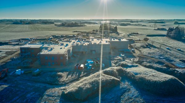 Dronefoto af byggepladsen med sol og blå himmel.